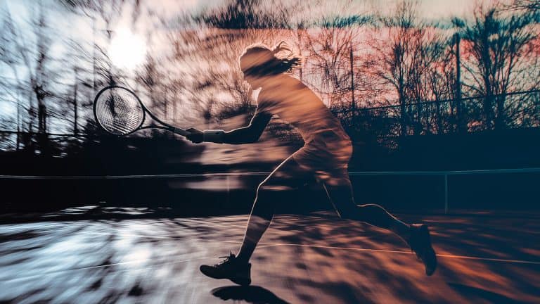 Double exposure of a silhouette of a tennis player swinging a racket in motion