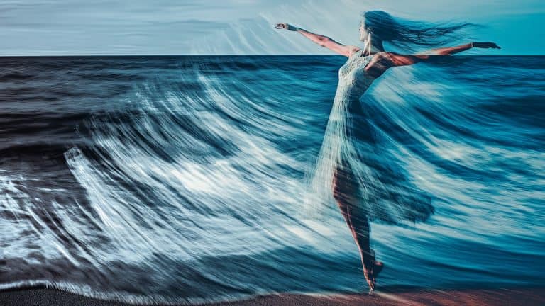 Double exposure of a woman dancing gracefully on a beach and ocean waves crashing: freedom and fluidity concept.