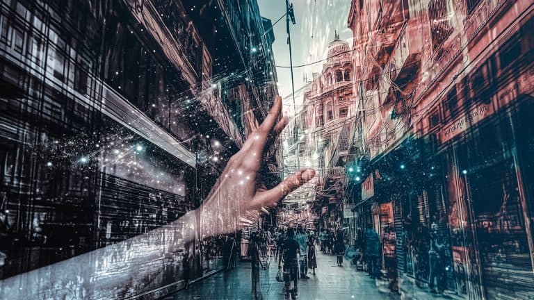 Double exposure of a hand reaching out against a cosmic background
