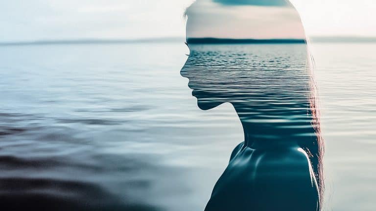Double exposure of a woman's profile silhouette and a calm ocean surface: tranquility and introspection concept.