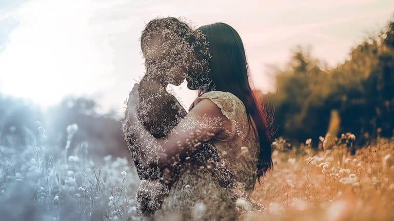 Double exposure of a couple embracing in a field and wildflowers in soft focus: love and nature concept.