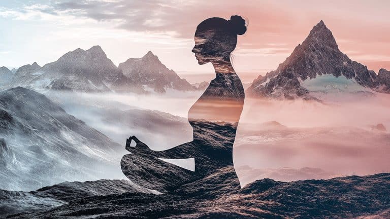 Double exposure of a silhouette of a woman meditating in lotus position and a misty mountain range at sunrise: tranquility and mindfulness concept.