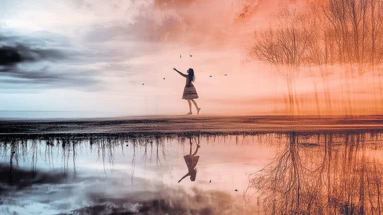 Double exposure of a girl reaching out surrounded by birds against a golden sky