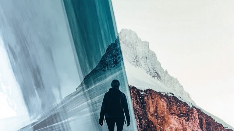 Double exposure of a person standing on a snowy mountain slope and a towering snow-covered peak with a rocky base: exploration and solitude concept.