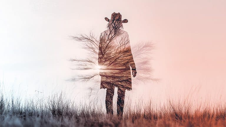 Double exposure of a silhouette of a person in a cowboy hat standing in a field