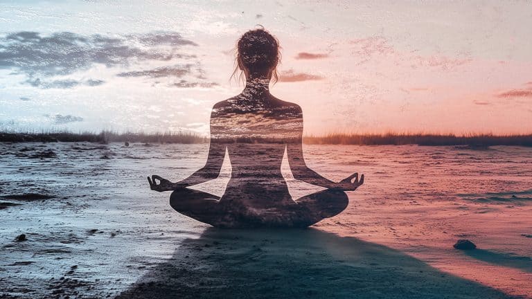 Double exposure of a silhouette of a person meditating in lotus position and a serene beach at sunset: tranquility and mindfulness concept.