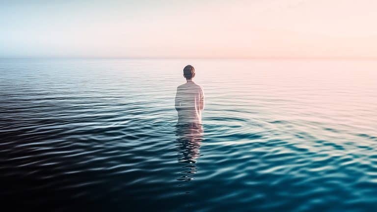 Double exposure of a person standing in a calm ocean viewed from the back
