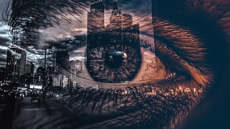 Double exposure of a close-up human eye and a city skyline at dusk with illuminated buildings: urban reflection and perception concept.
